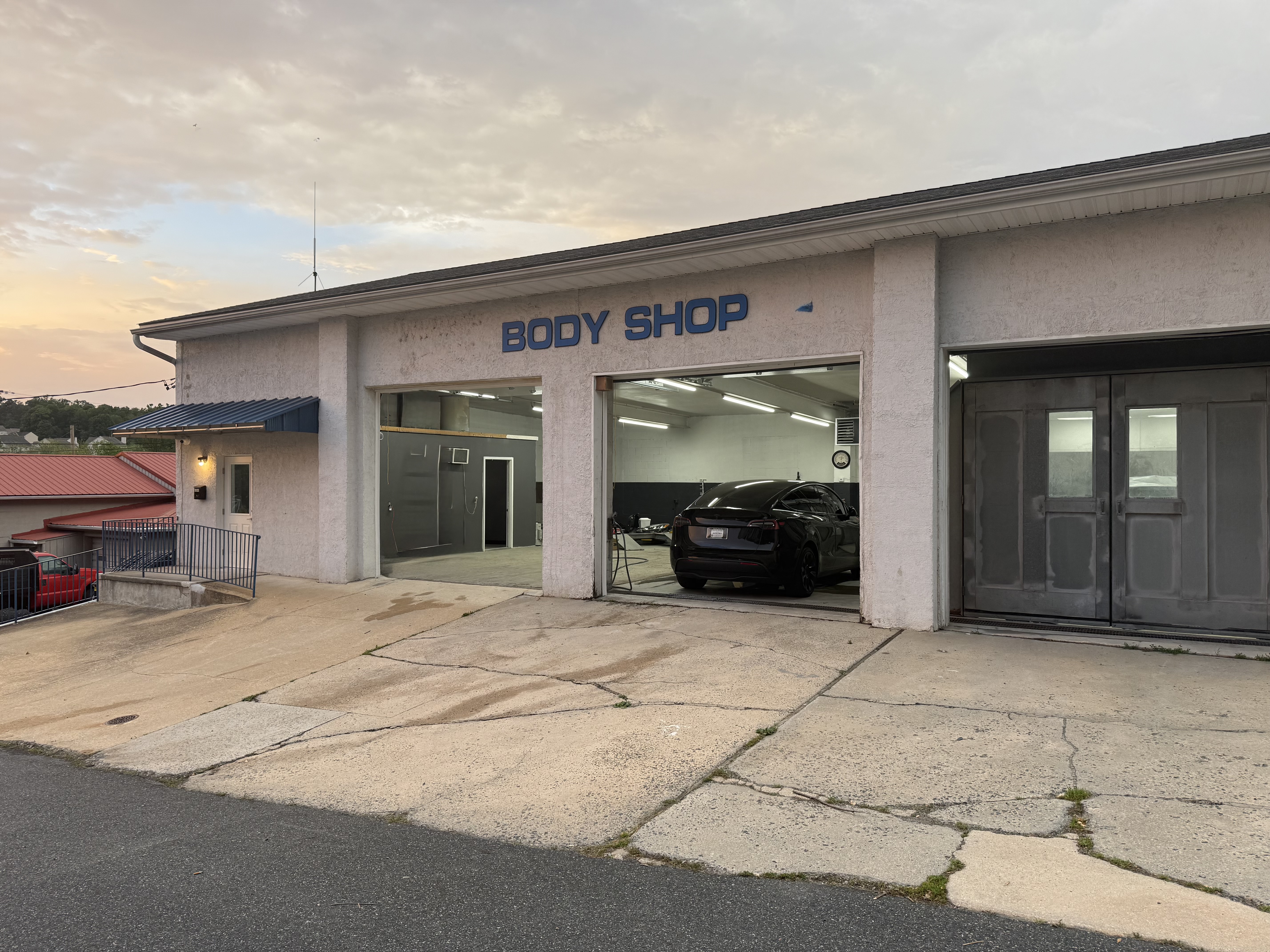 Wide angle of body shop building with signage and open bays